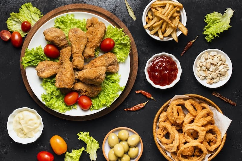 Various processed foods are shown like chicken wings, onion rings, and french fries
