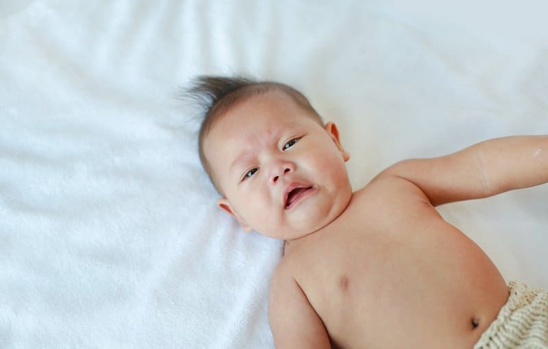 A young baby boy is laying on his back, and is not feeling well because of his nasal congestion.