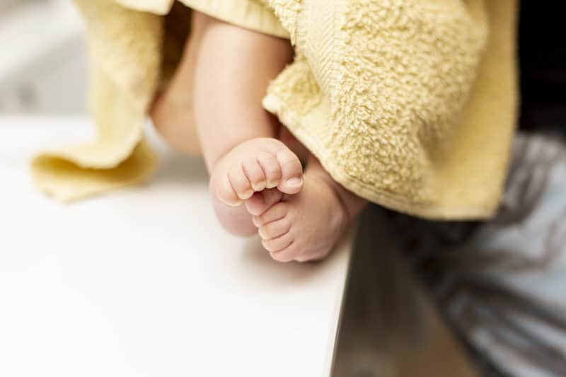 Baby wrapped up in a yellow towel after bath time.