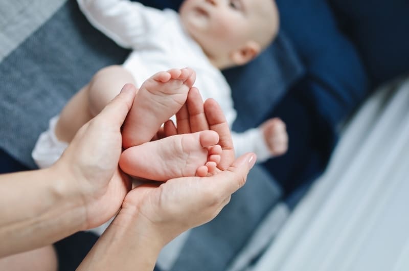 Parent looking at their baby's feet to look for symptoms of excessive foot rubbing that can happen during their infant stage.