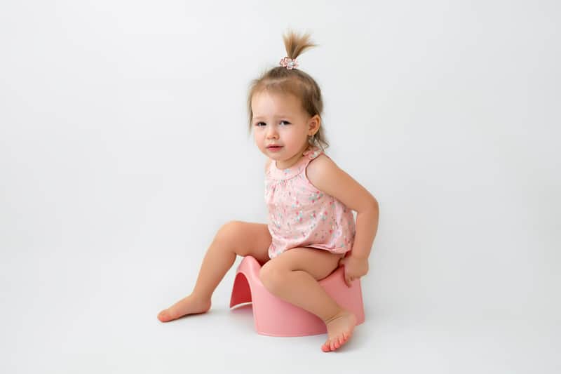 Toddler girl sitting on the potty crying, because she might be constipated.