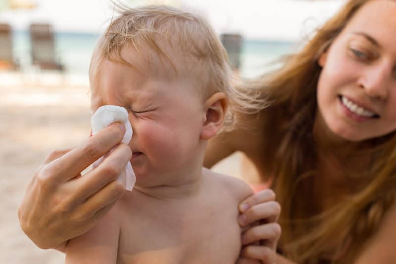 Mom helping her baby blow his nose, who has a cold.