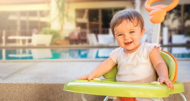A happy young baby girl sitting in her walker, smiling with lots of energy.