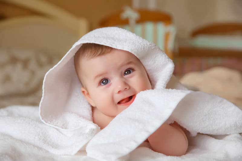 A cute infant boy is wrapped up in a white towel.