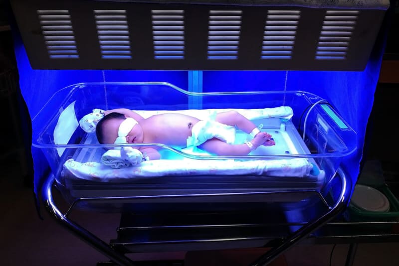 A newborn baby is laying down and getting light therapy done to treat his jaundice.
