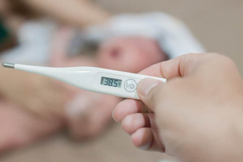 Mom is showing a thermometer with a high 38.5-celsius temperature, which might be a sign of sepsis in her newborn.