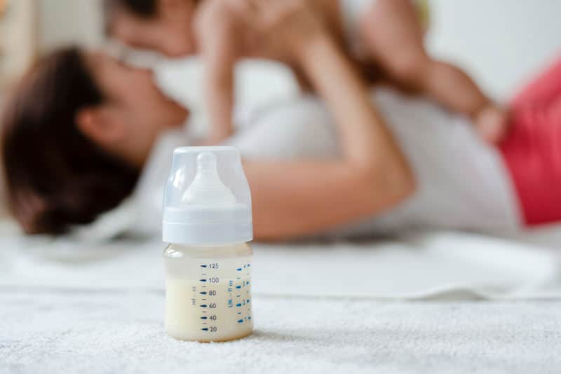 A mom is bottle feeding her own breast milk to her infant baby.