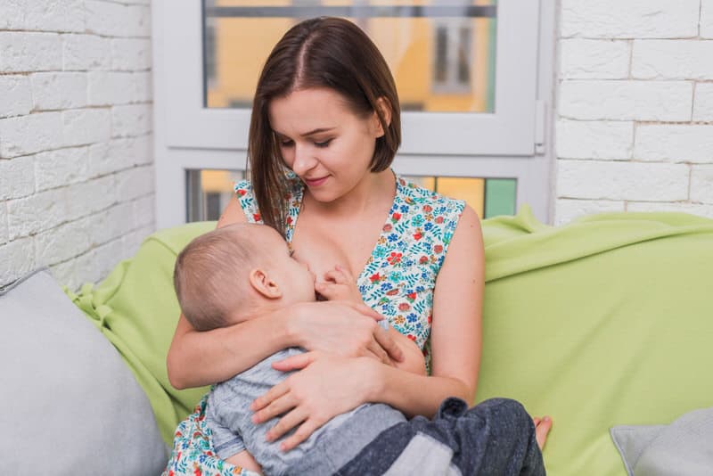 A young mom is breastfeeding her infant son as a treatment for swollen lymph nodes caused by teething.