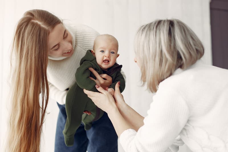 Grandma is interacting with her newborn grandson, and mom has asked that she not kiss the baby.