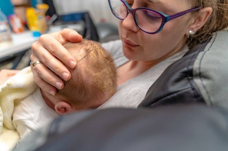 A mom is with her baby boy at the doctors, who is getting diagnosed for his cradle cap.