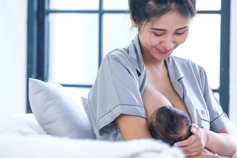 A young mom is breastfeeding her newborn baby.