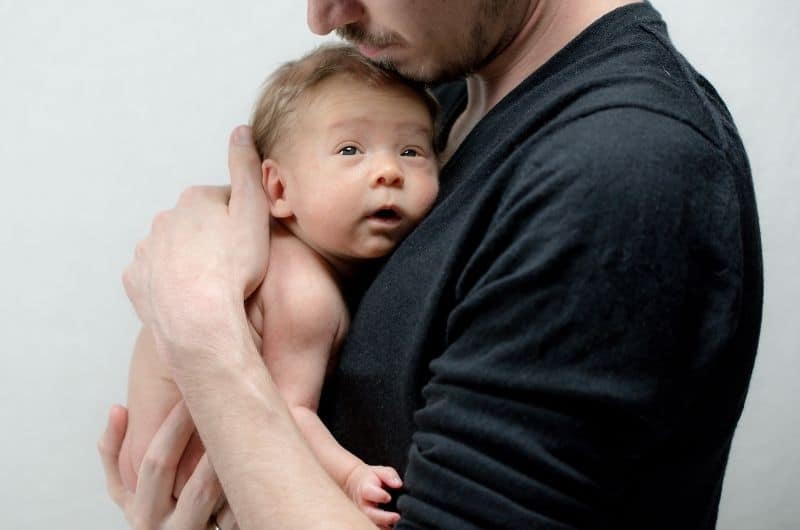 Dad bonding with his newborn son by holding him.