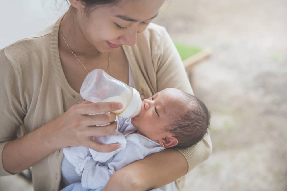 A mom is feeding her newborn baby formula milk.
