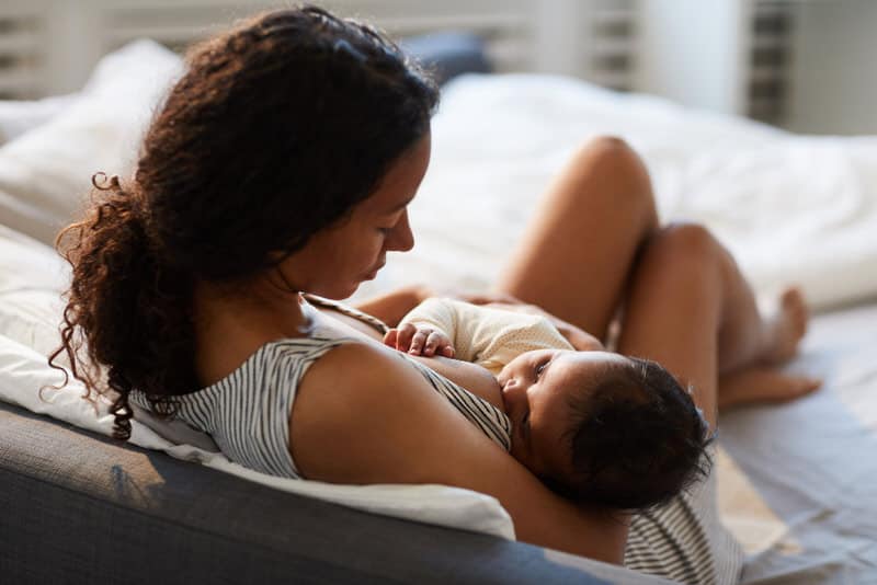 A young mom is breastfeeding her newborn baby often, and in a proper position and latch, to help prevent any pain and plugged breast ducts.