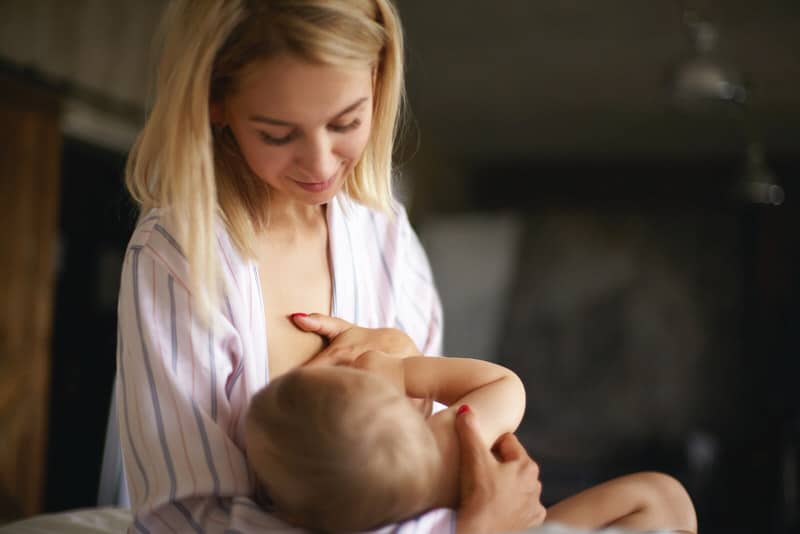 A mom is happily breastfeeding her baby after being able to fix her lipstick nipple latching issue.