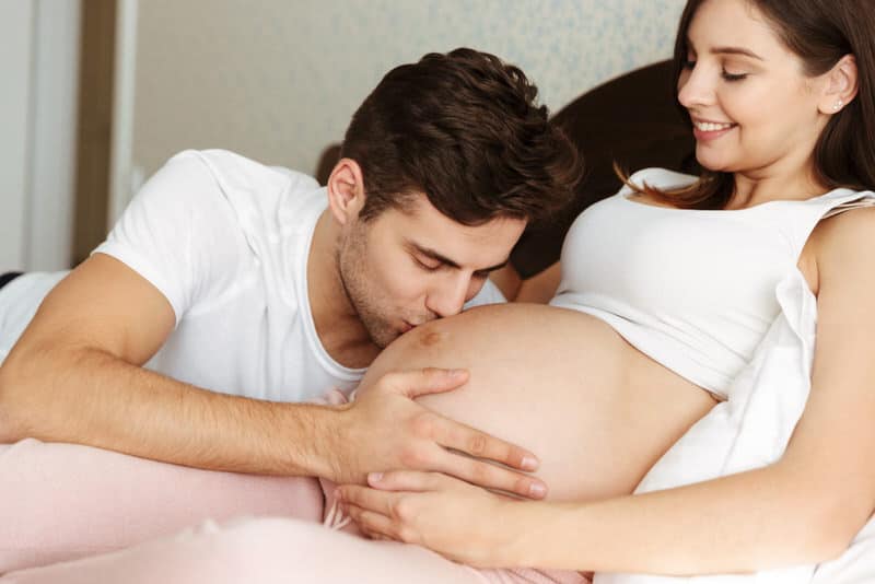 A happy young couple are bonding over the spouses pregnancy.