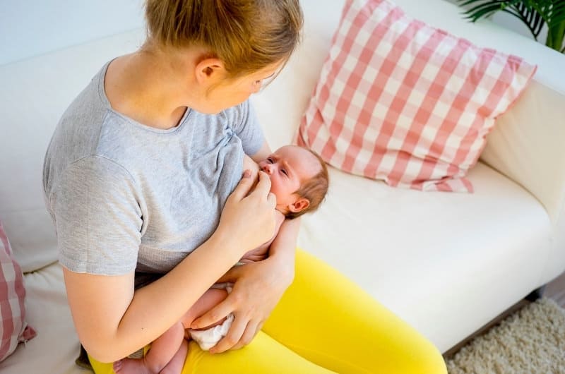 A young mom is breastfeeding her newborn baby.