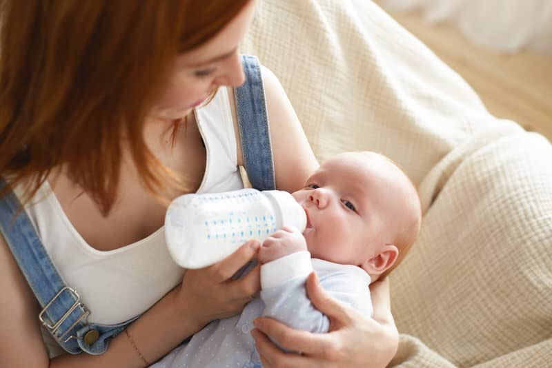 Mom is bottle feeding her newborn baby formula milk after finding that breastfeeding causes her baby discomfort due to lactose intolerance.