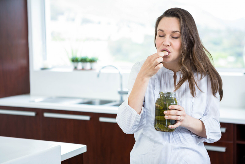 A pregnant woman who has been craving pickles is finally enjoying some in her kitchen.