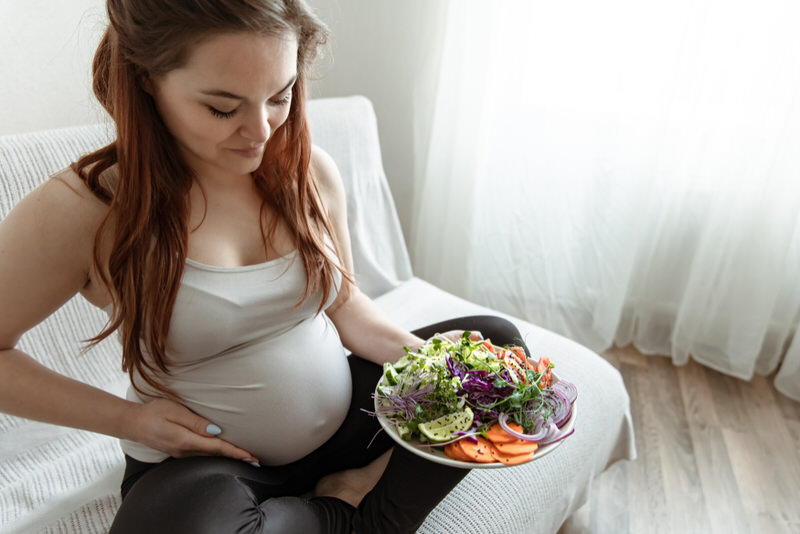 A pregnant woman is trying to increase her weight healthily by eating a salad.