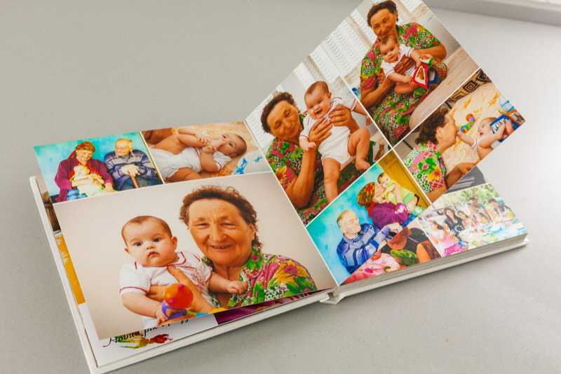A custom family book is opened showing different pictures of a newborn baby with his family.