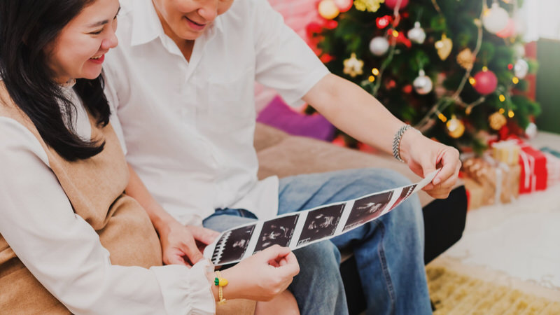 A young pregnant couple is looking at a recent baby sonogram that they'll use soon to reveal their pregnancy to immediate family members.