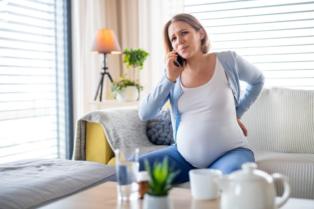 A pregnant woman is feeling labor contractions and is on the phone with her husband