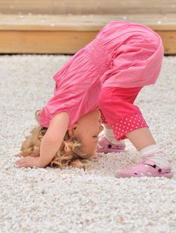 A toddler girl is practicing the downward dog pose as a recent milestone she's been able to do