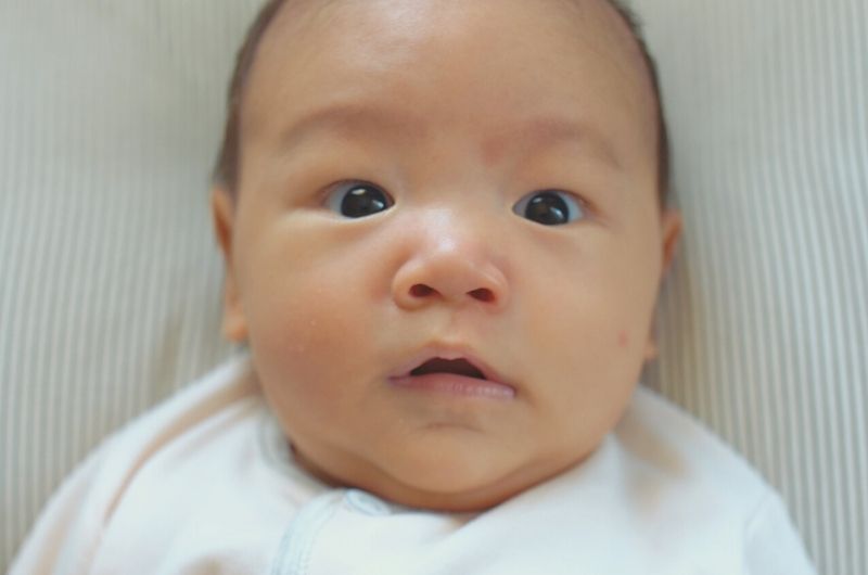 A newborn boy is cooing and using his eyebrows as a way to communicate with his parents