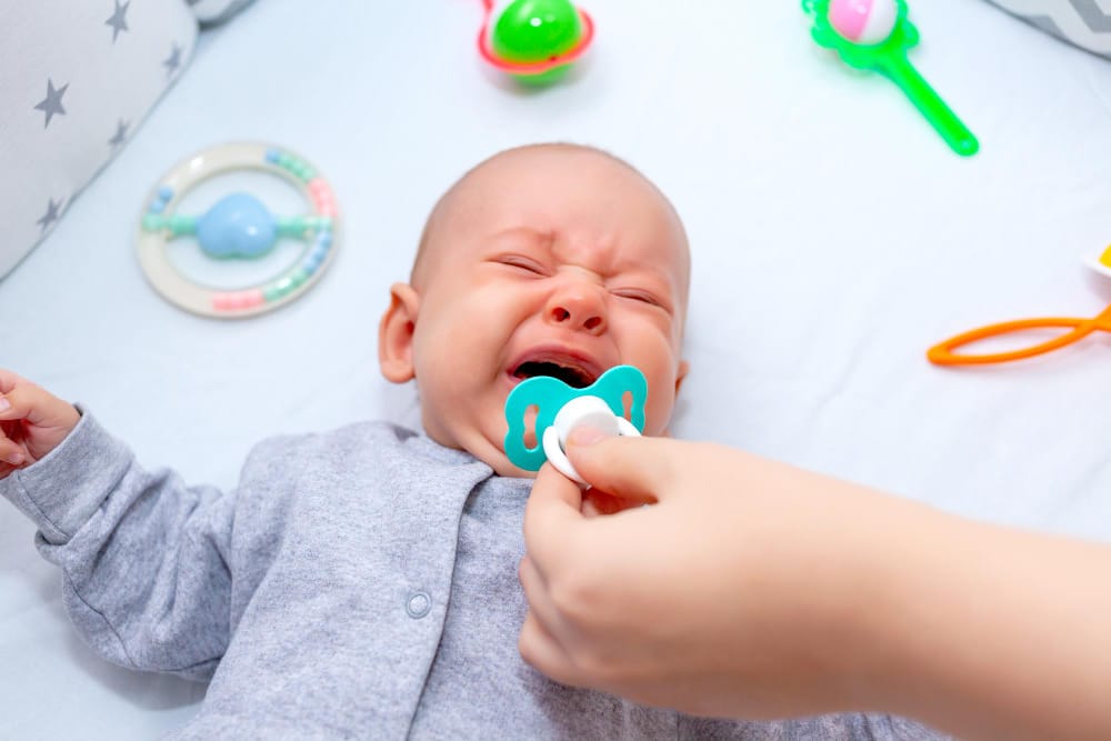 A mom is soothing her colicky newborn baby with a pacifier