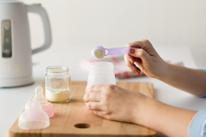 A mom is adding rice cereal to some breastmilk in a bottle to feed her infant baby