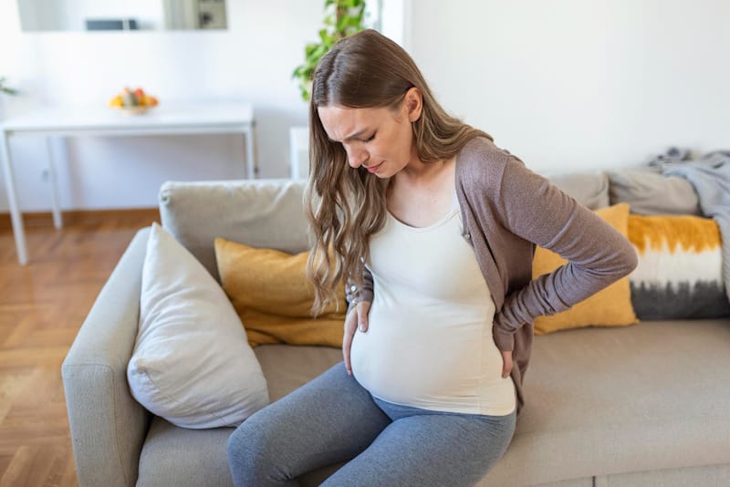 A pregnant woman is sitting down because she's feeling pain 