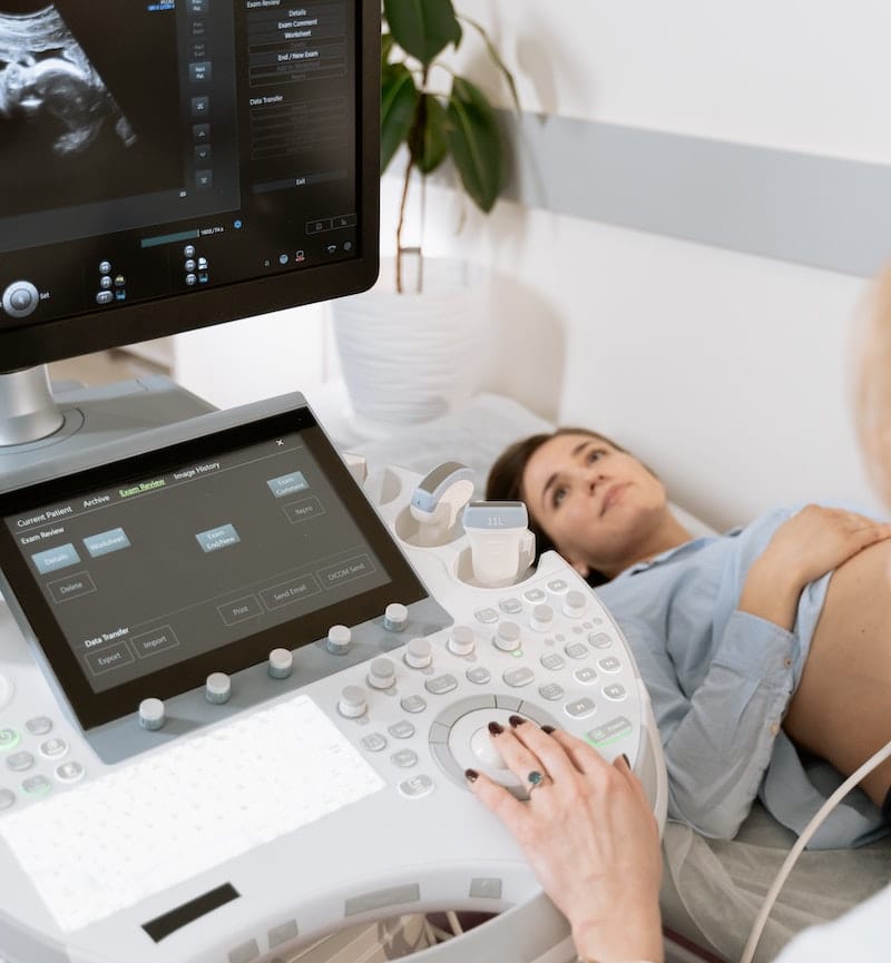 A pregnant woman is laying down getting an ultrasound done of her baby