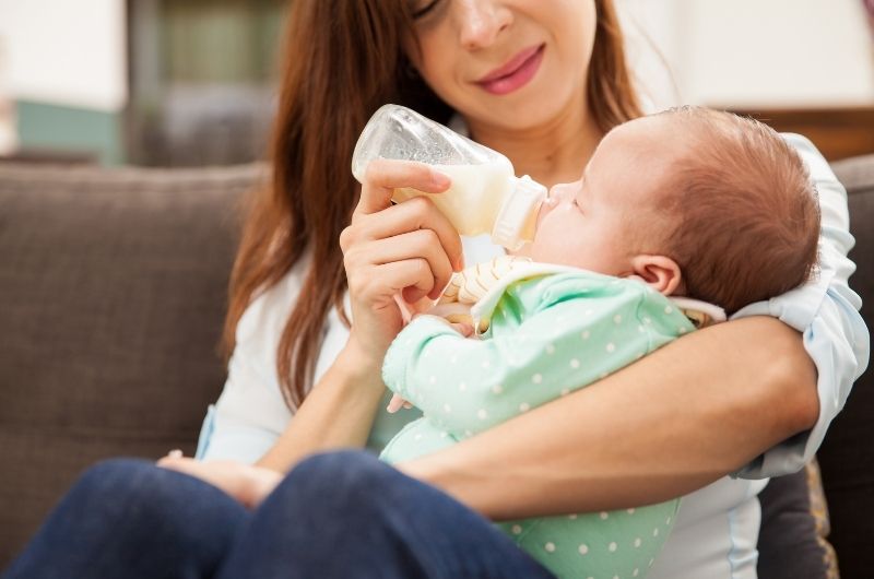 A mom is bottle-feeding her infant son, who she is gradually transitioning from breastmilk to formula milk.