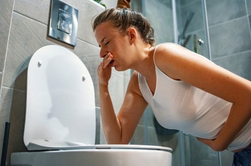 A young pregnant woman is in the bathroom experiencing morning sickness