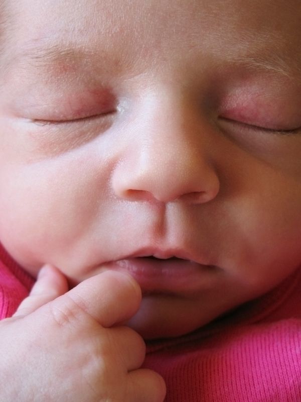 A newborn baby's chin is quivering as he is sleeping