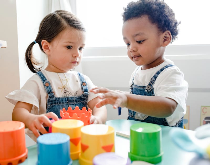 Two toddler children are playing with toys together