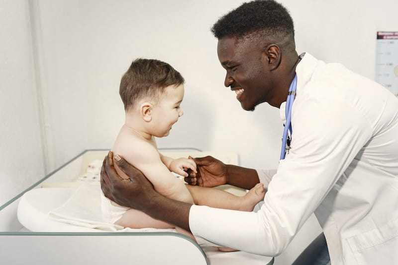 A pediatrician is looking at a baby boy to check his health status