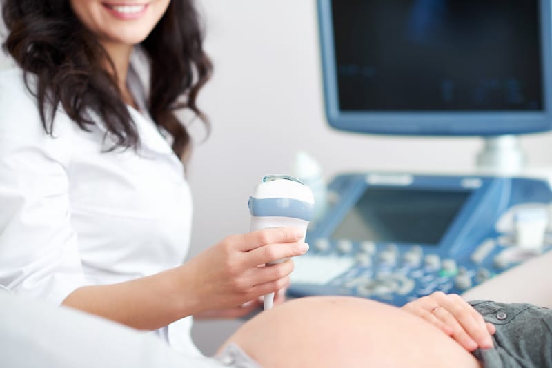 A pregnant woman is about to get an ultrasound done by her gynecologist