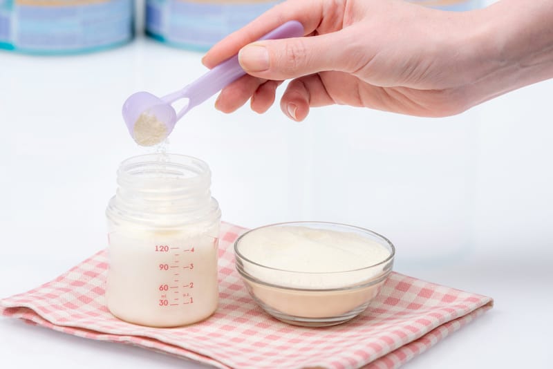A mom is preparing a bottle of organic formula milk for her infant