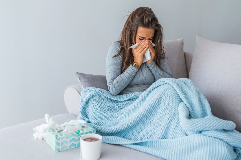 A young pregnant woman is feeling cold and has a runny nose, indicating she might have a mild fever.