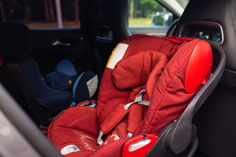 An old infant car seat is being reviewed by a parent to see if it's safe to reuse or needs to be recycled