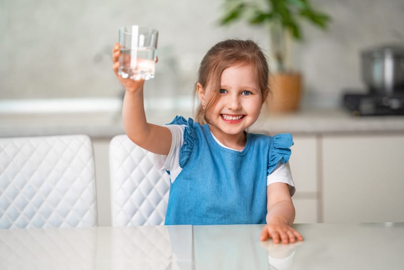 A toddler girl is drinking water to hydrate after she vomited a lot