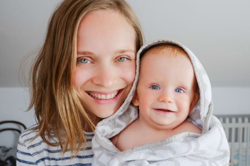 A cheerful mom with her infant after giving a nighttime bath to induce deep sleep.