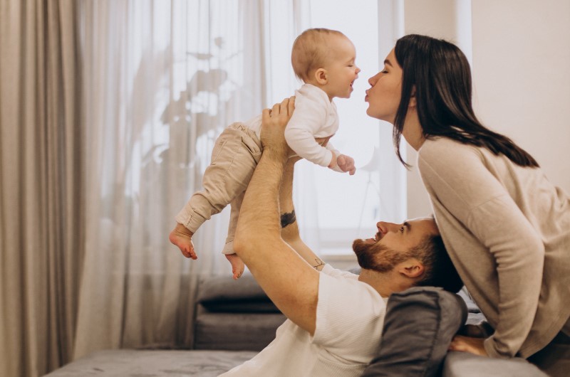 Parents are happily playing with their infant  during the day to induce better sleep at night.