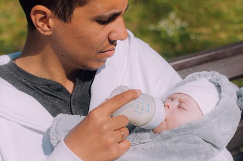 A dad is bottle-feeding his baby but is worried about a formula shortage in the market. 