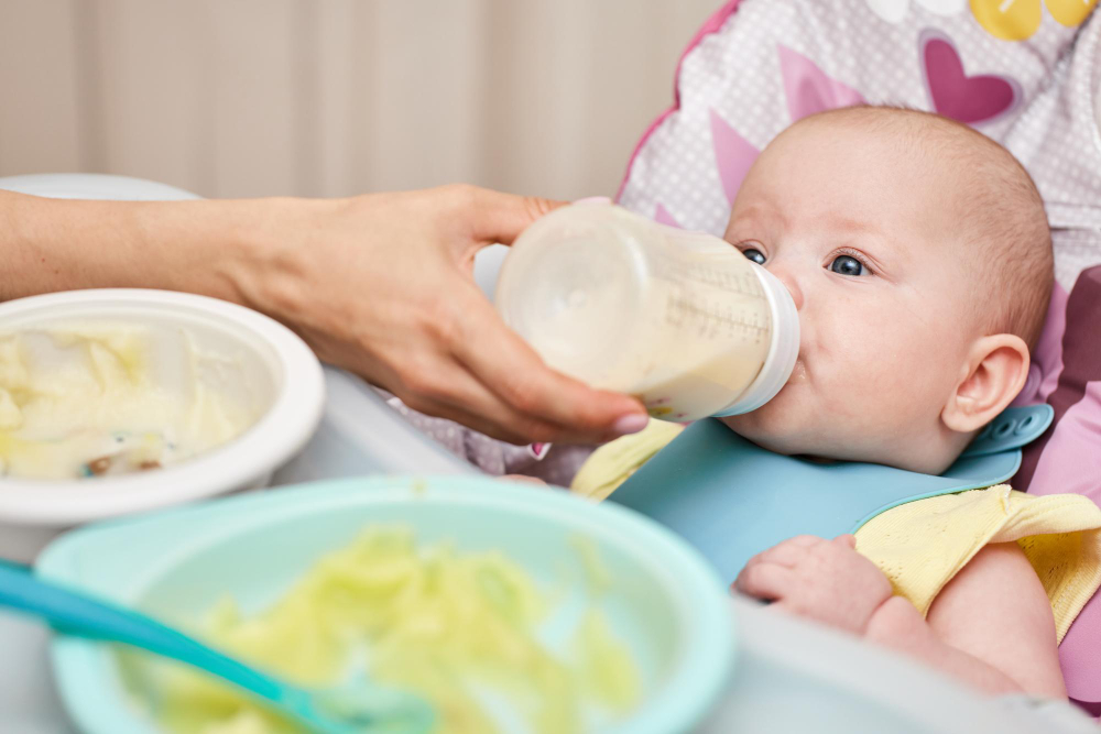 An infant baby is drinking formula milk from a bottle