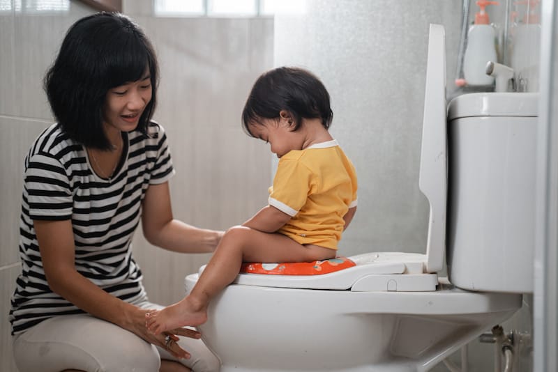 Mom is helping her toddler daughter get used to using the potty and how to wipe herself clean when she's finished.