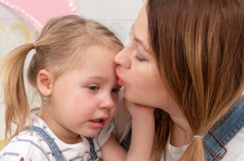 A mother is soothing her crying child who has an ear infection
