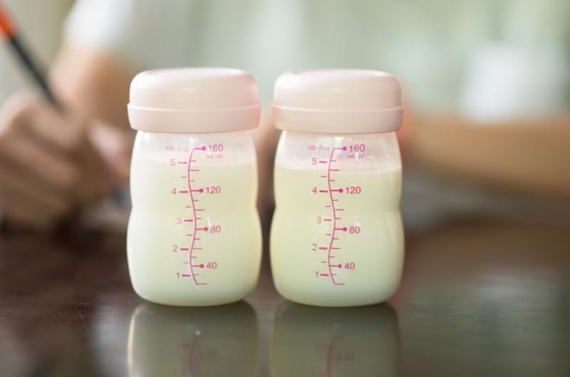 Mother writes different ways and quantities of formula milk to be stored in the fridge. 